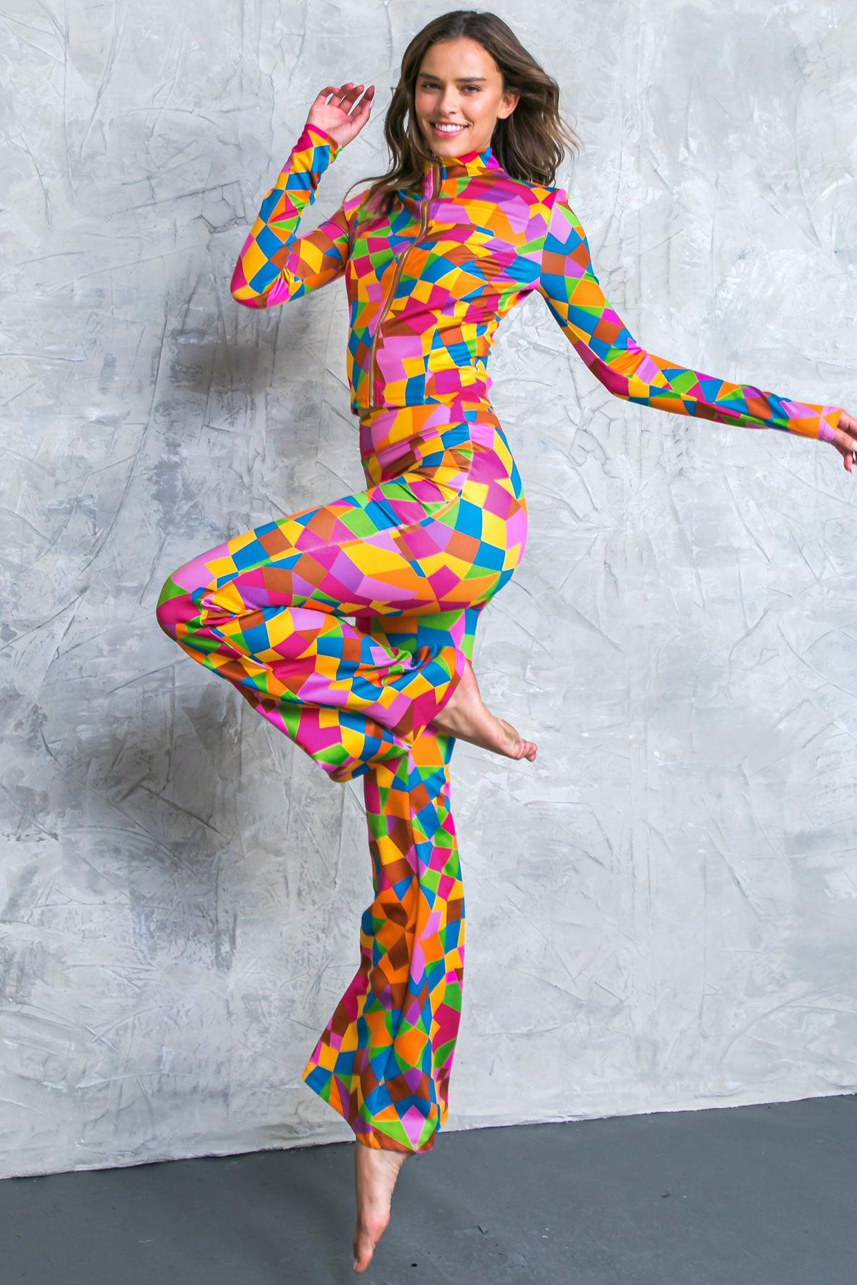 Model wearing a multi-color geometric print scuba tracksuit with a zip-front top and flare leg pants.
