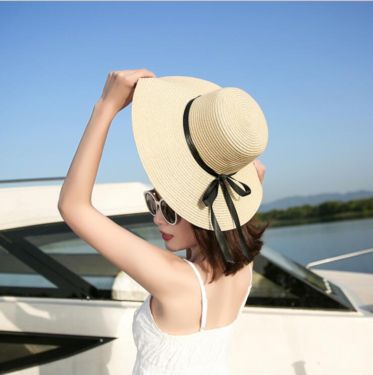 Young girl wearing a trendy, foldable wide-brim straw sun hat at the beach