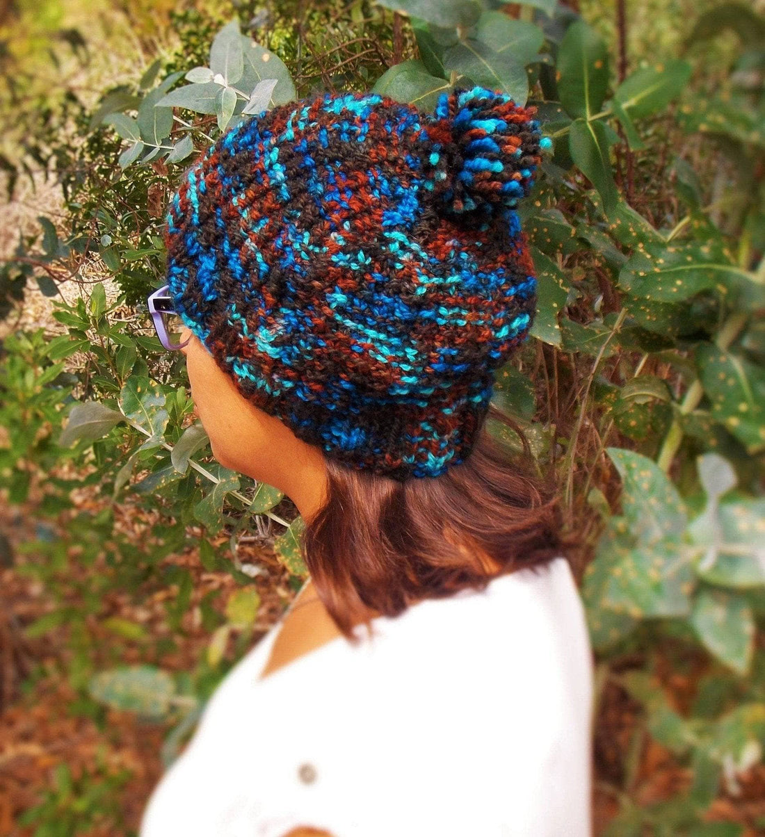 A stylish, handmade slouchy knit hat in variegated black, blue, and rust tones, showcasing a bohemian winter aesthetic.