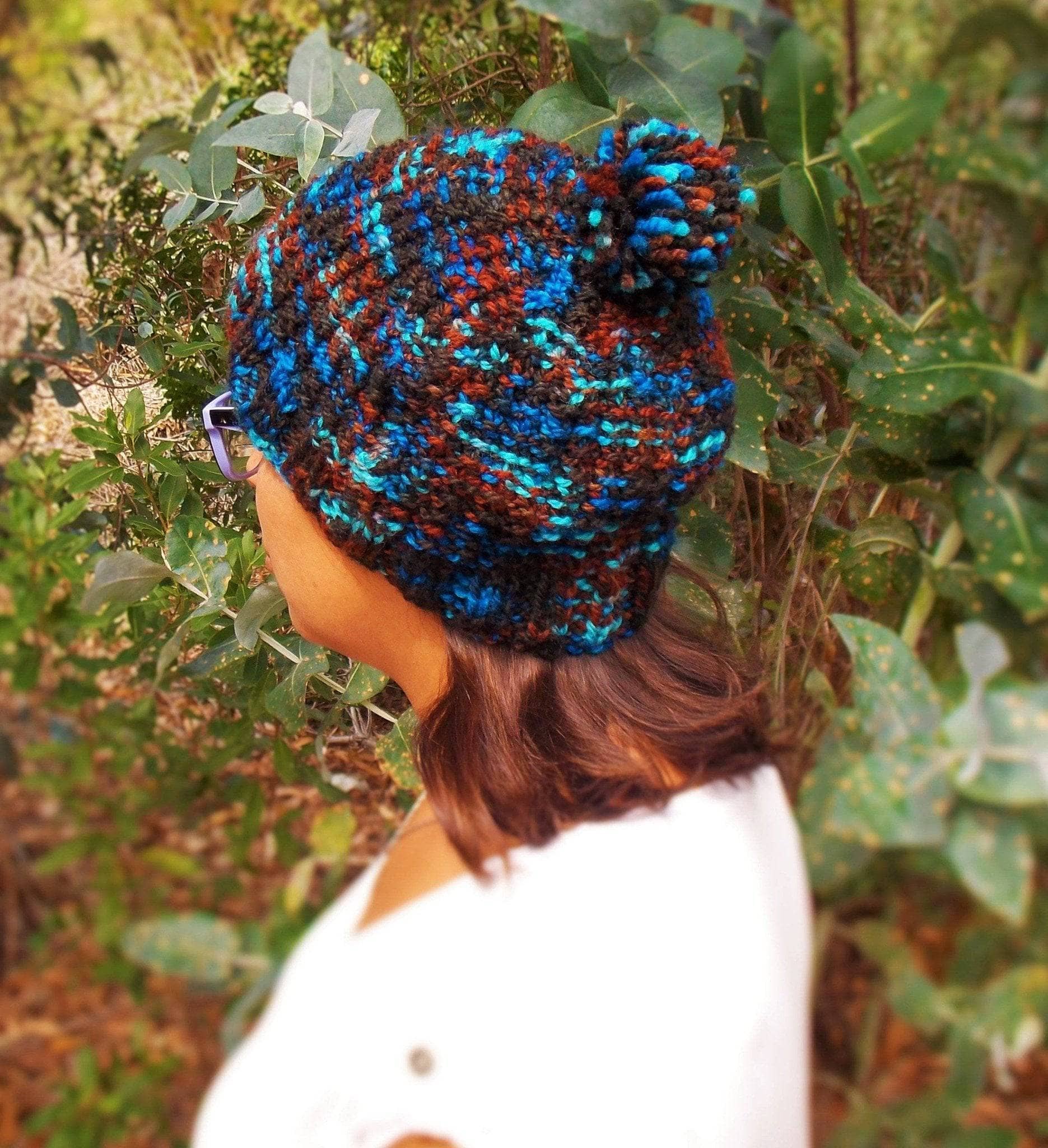 A stylish, handmade slouchy knit hat in variegated black, blue, and rust tones, showcasing a bohemian winter aesthetic.