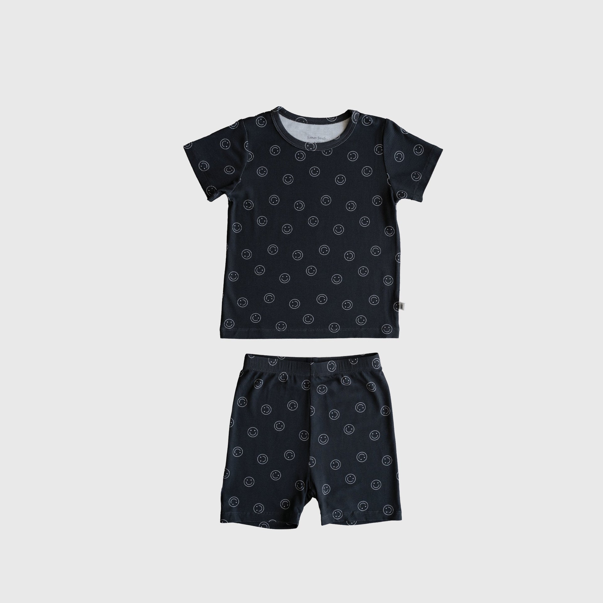 Child wearing a black and white smiley face ribbed bamboo crew neck short set