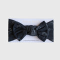 A charcoal grey ribbed baby head wrap with white smiley face line art and a decorative bow.