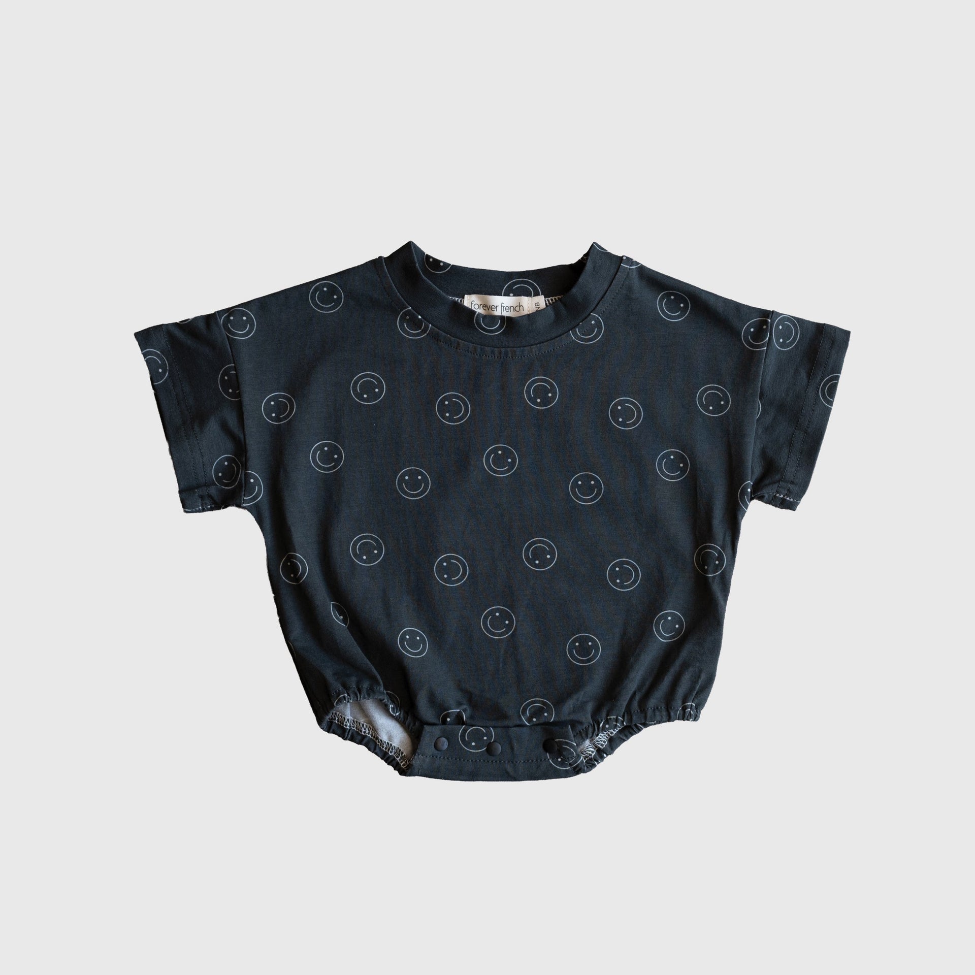 Baby wearing a minimalist charcoal grey and white smiley print short sleeve cotton romper