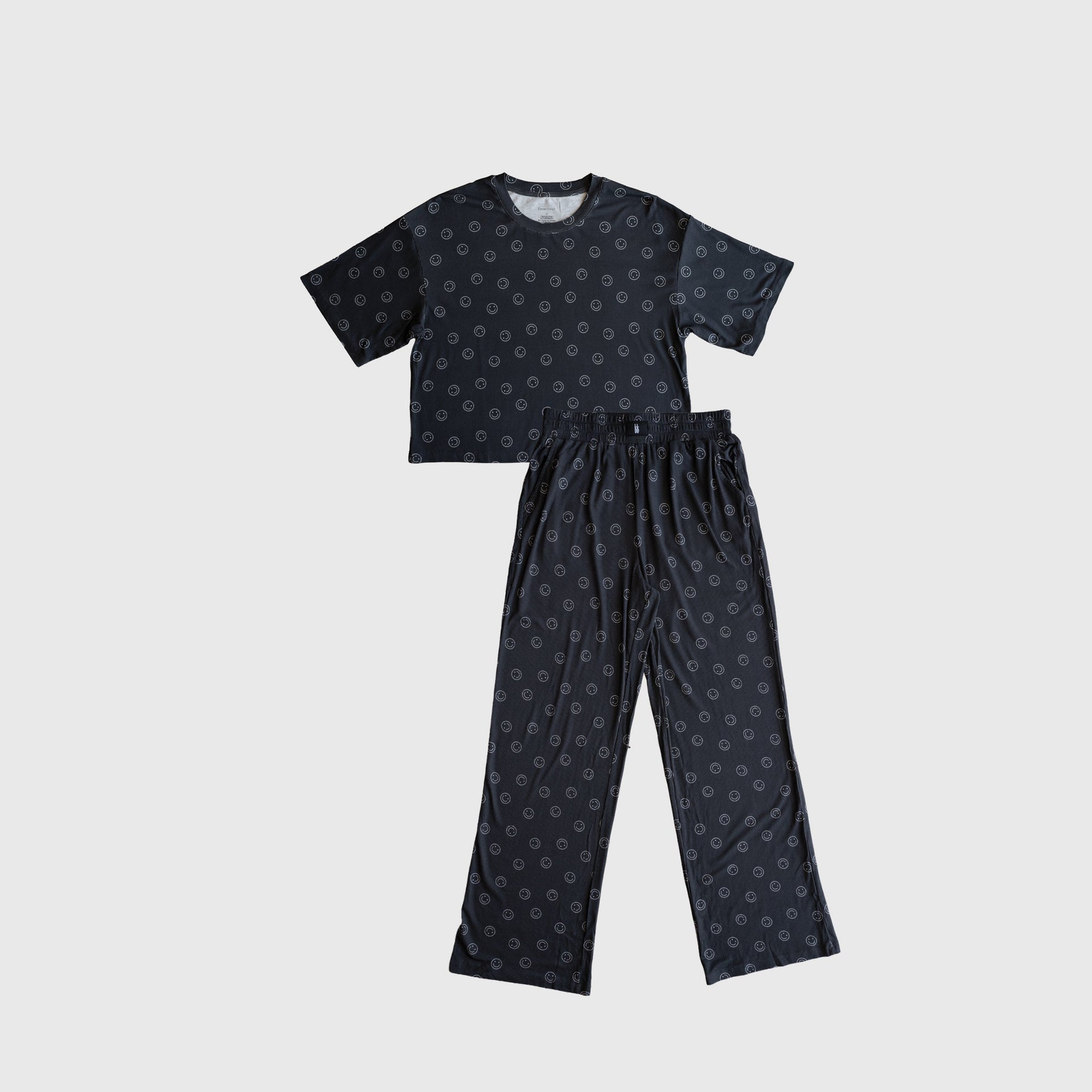 Woman wearing a black and white boxy tee and wide-leg lounge set in a minimalist setting.