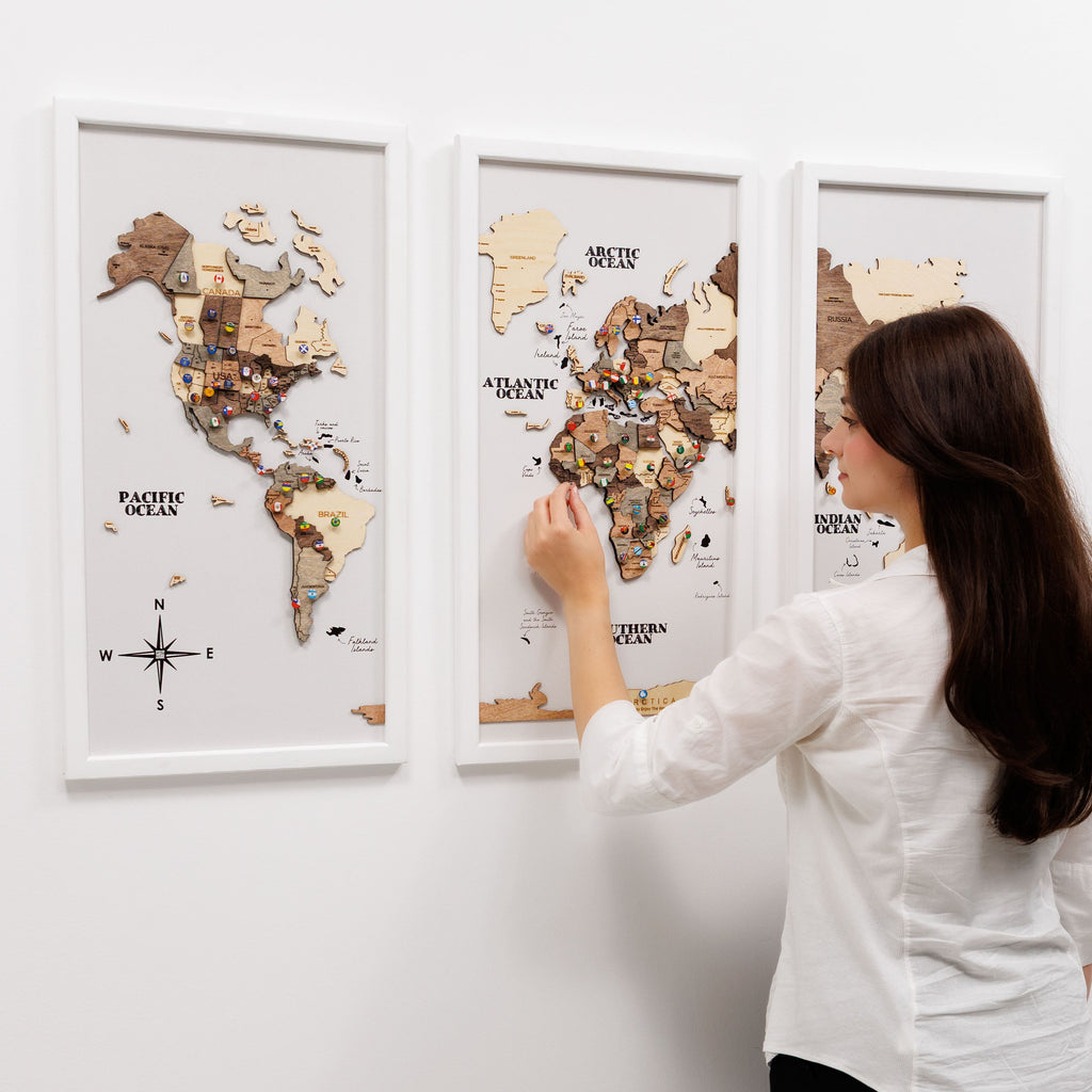 Triptych wooden world map wall art in a dark smokey finish displayed on a modern living room wall.