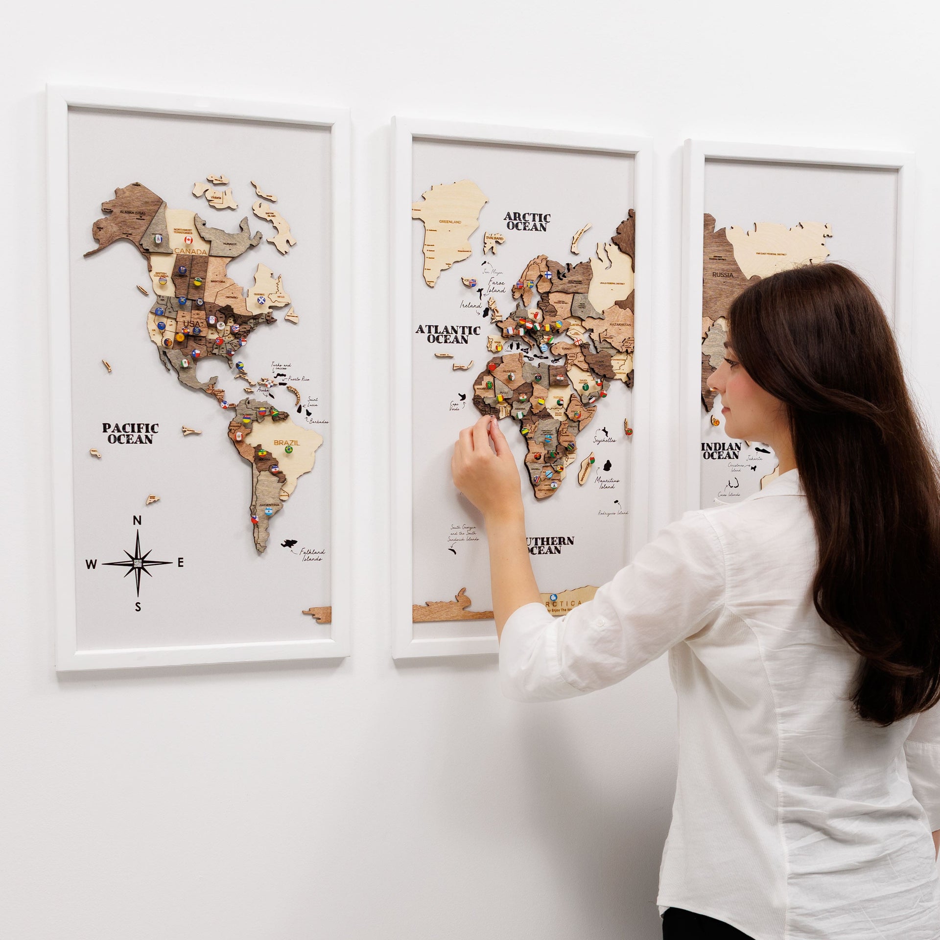 Triptych wooden world map wall art in a dark smokey finish displayed on a modern living room wall.