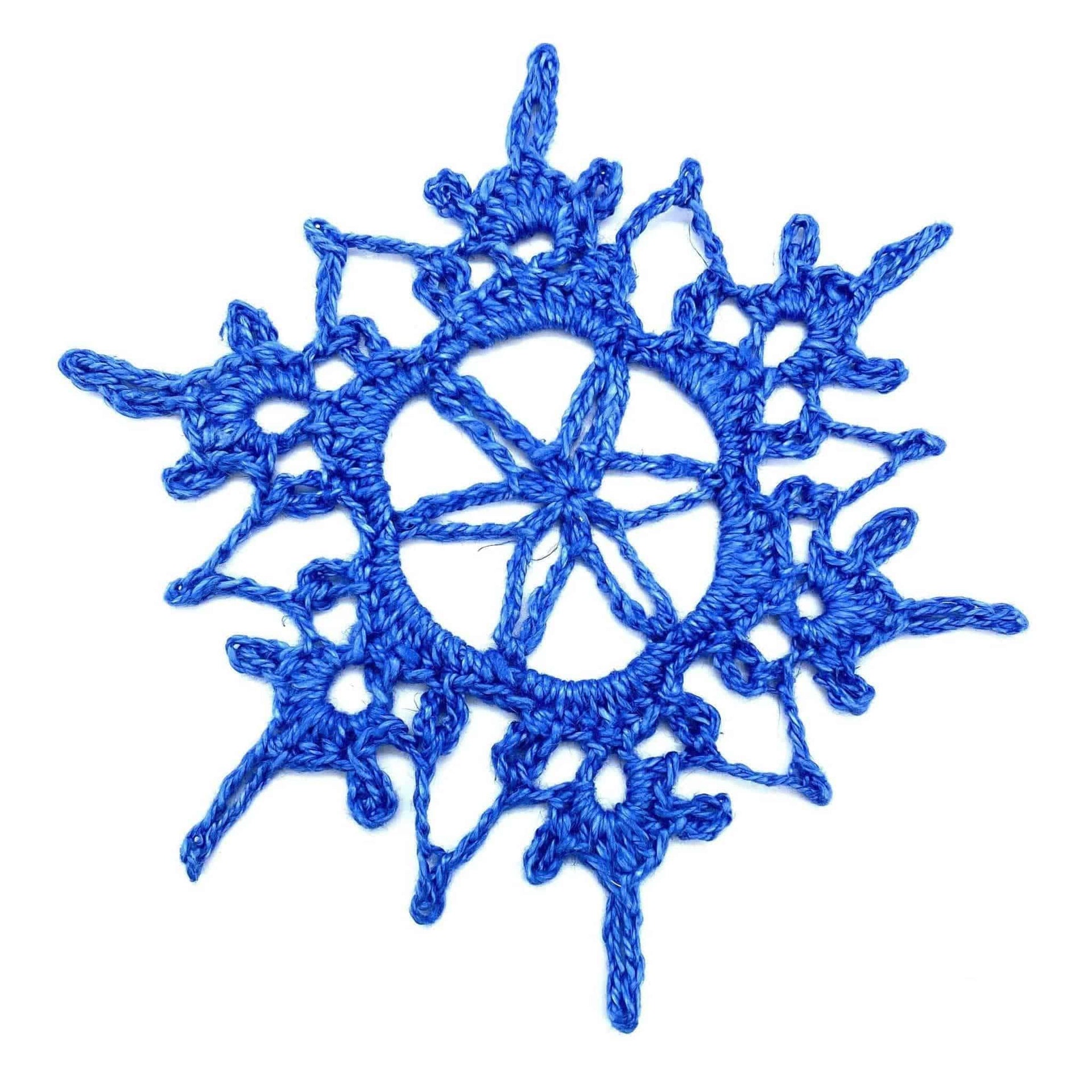Close-up of a royal blue handmade knit snowflake doily set on a surface