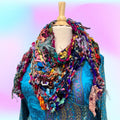 Vibrant bohemian shawl featuring multi-colored yarn in fuchsia, teal, mustard, and purple.