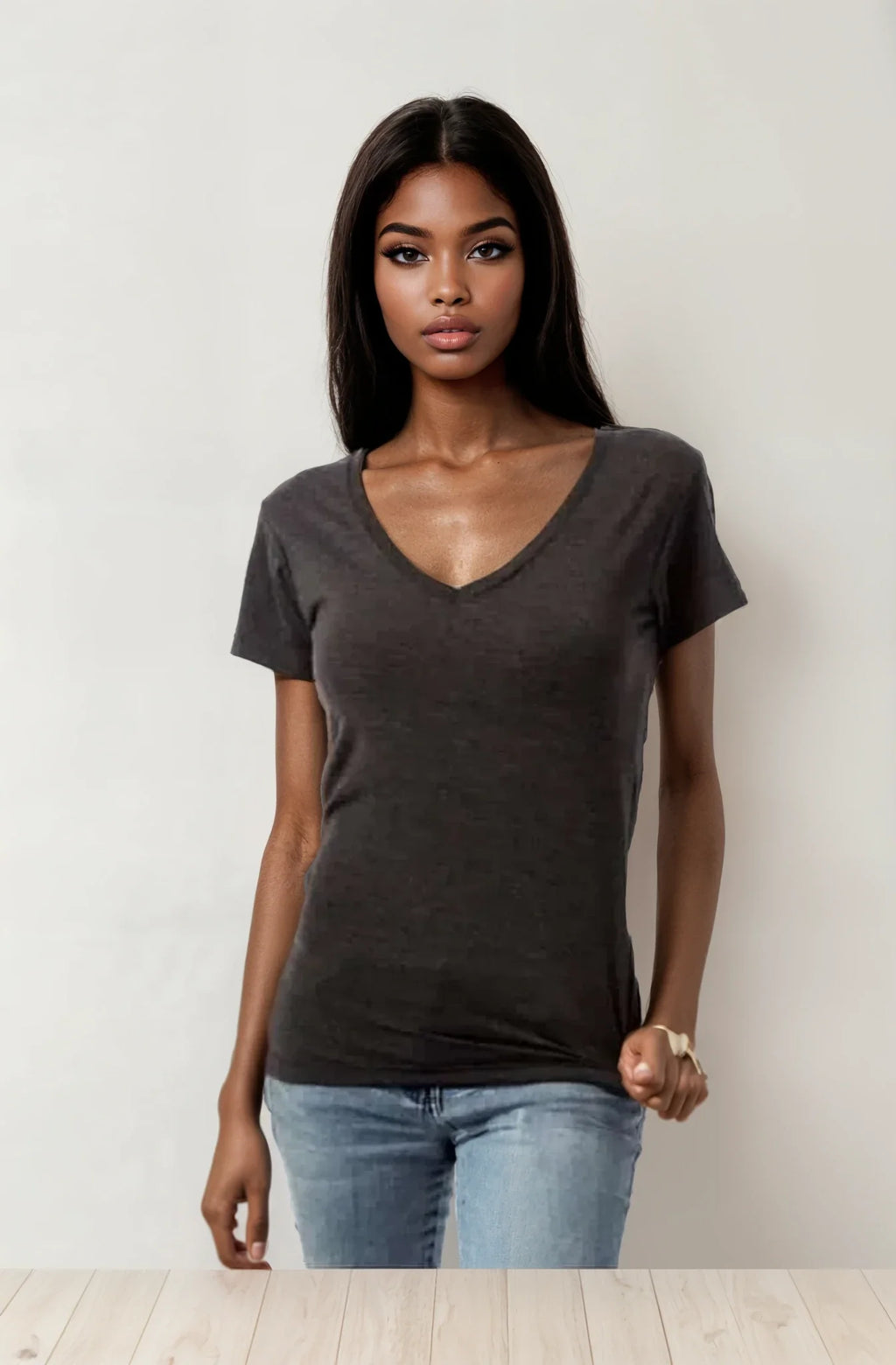 A woman wearing a dark grey V-neck short sleeve t-shirt, standing against a neutral background.