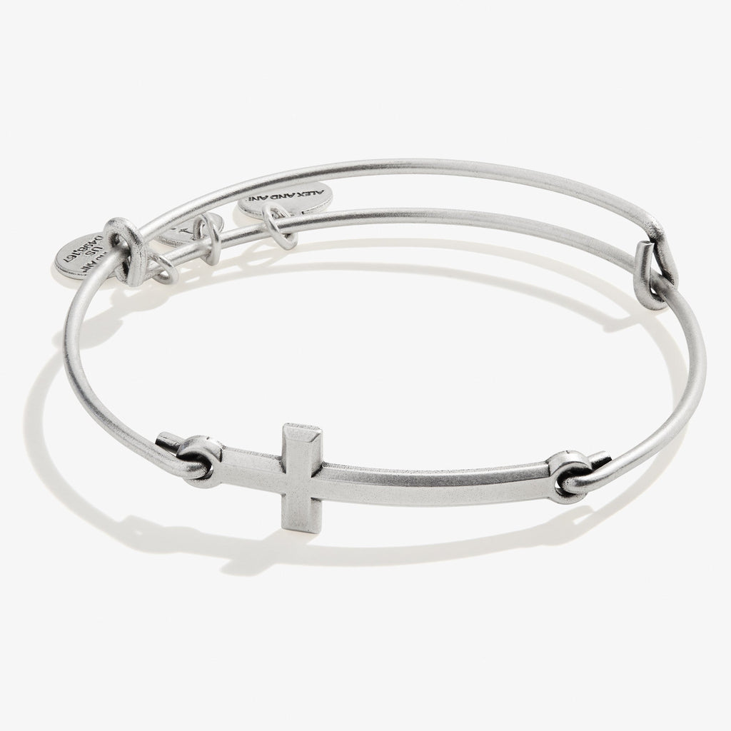 Elegant silver-tone minimalist cross charm bangle on a neutral background.