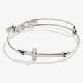 Elegant silver-tone minimalist cross charm bangle on a neutral background.
