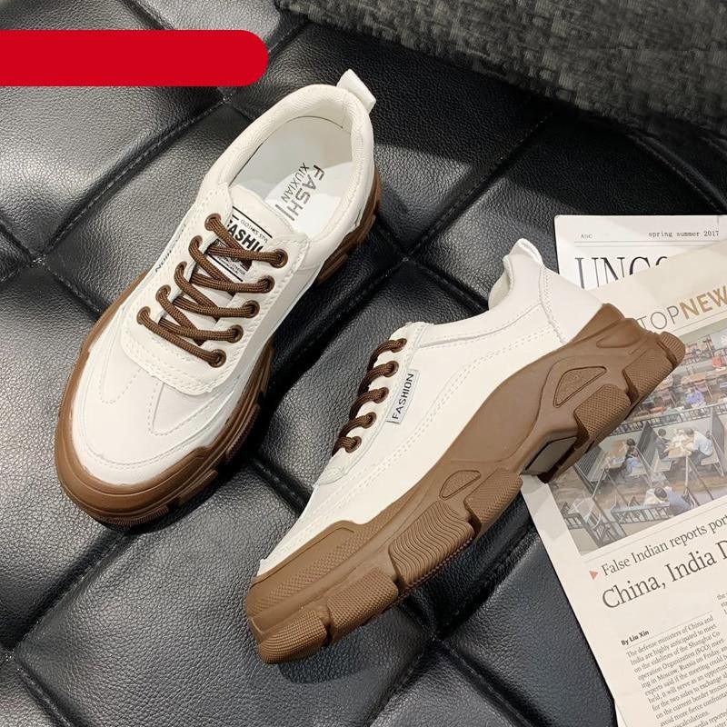 A pair of clean white lace-up platform sneakers for women viewed from the side on a plain background.