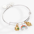 Silver and gold tone expandable bangle featuring enamel rainbow, four-leaf clover, and pot of gold charms.