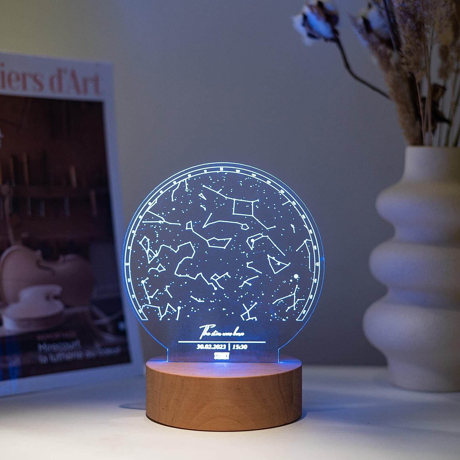 Custom star map night light with transparent acrylic and a natural wood base on a minimalist living room shelf.