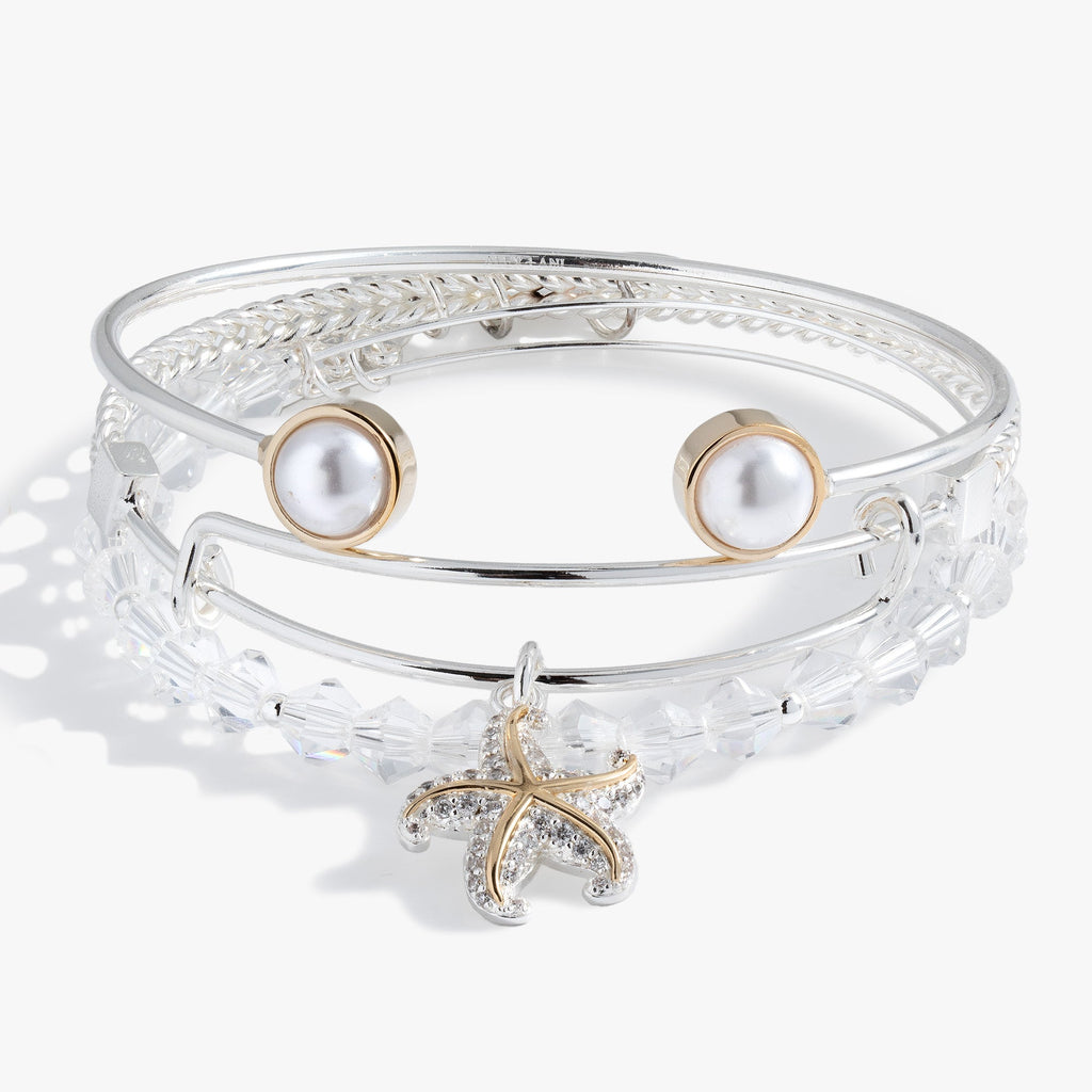 A set of three two-tone starfish, crystal, and pearl bangles worn as a stack.