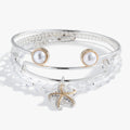 A set of three two-tone starfish, crystal, and pearl bangles worn as a stack.