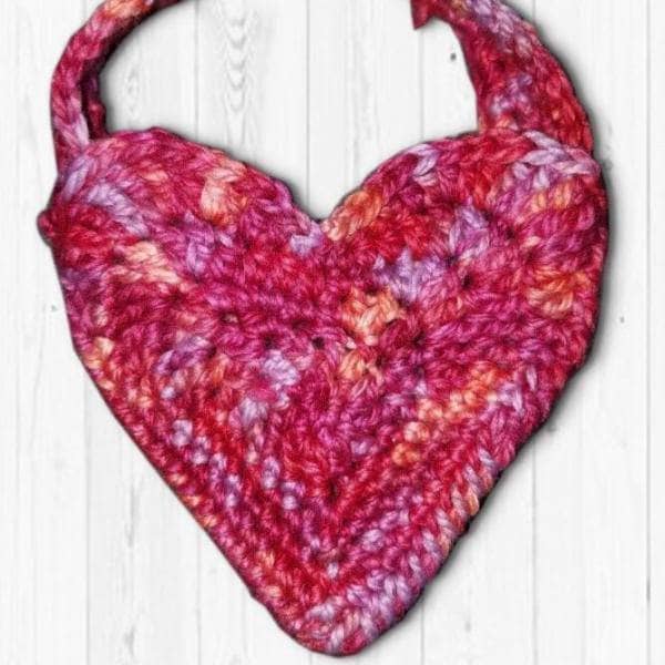Close up of a handmade crochet pouch pattern in a heart motif design