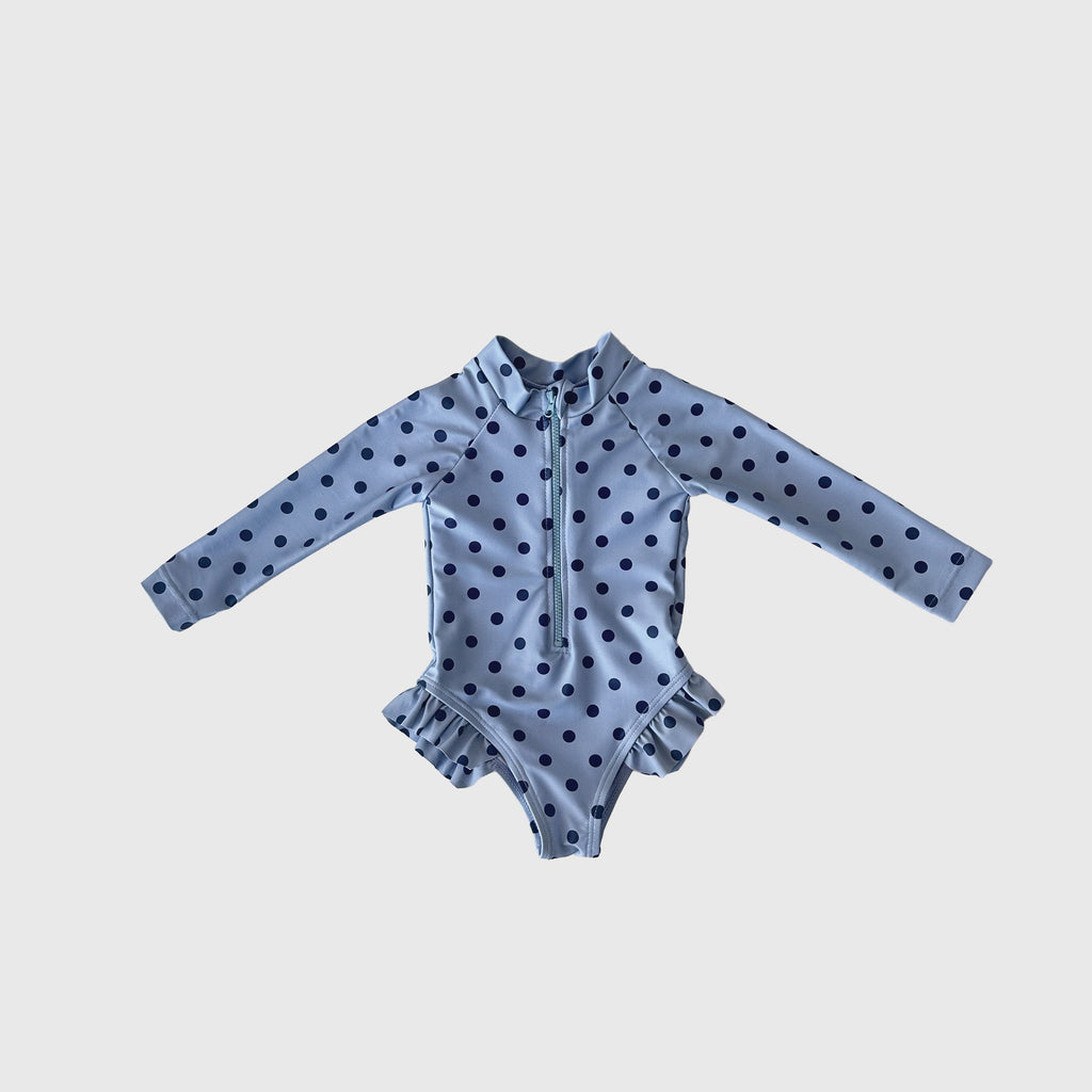 Girl wearing a long sleeve Sully polka dot one-piece swimsuit with ruffle leg details