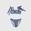 Woman wearing a classic polka dot bandeau two-piece swimsuit with adjustable shoulder ties in light-blue.