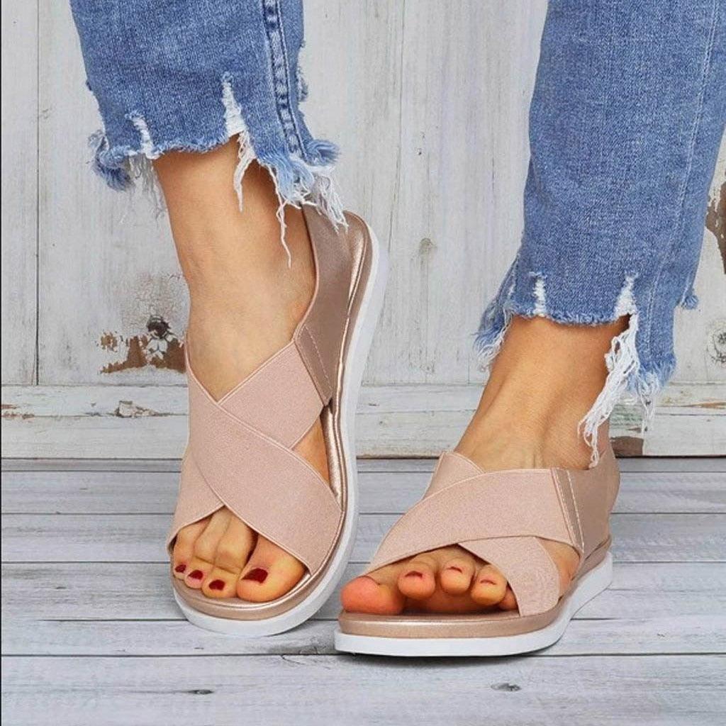 Close-up of women's comfortable elastic strap slip-on flat sandals in a casual beach setting