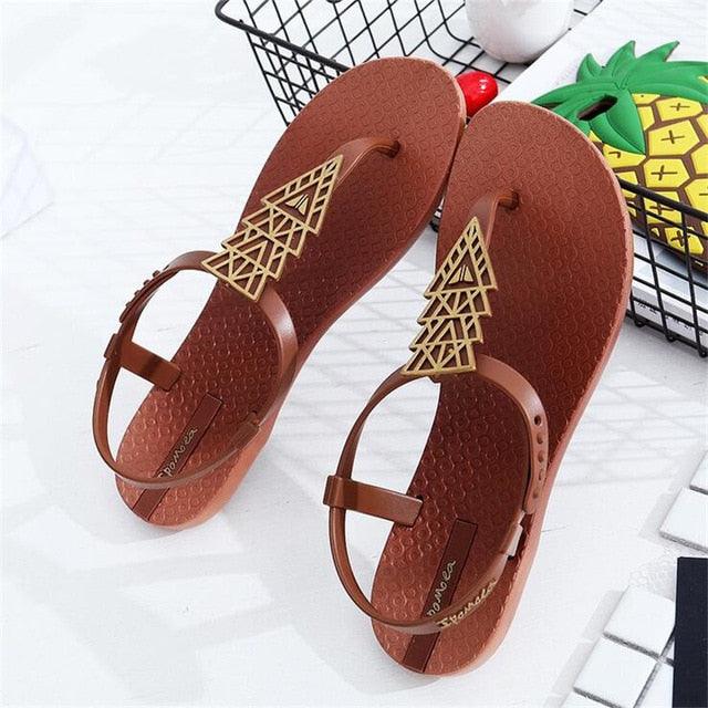 A pair of women's geometric pattern flat thong sandals in black and brown.