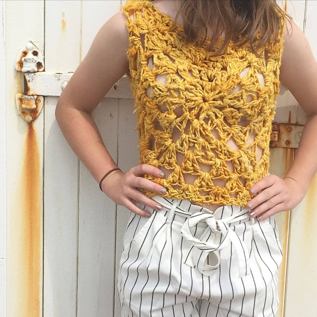 A handmade lace-style crochet tank top made from recycled banana fiber yarn, displayed in a sunny outdoor setting.