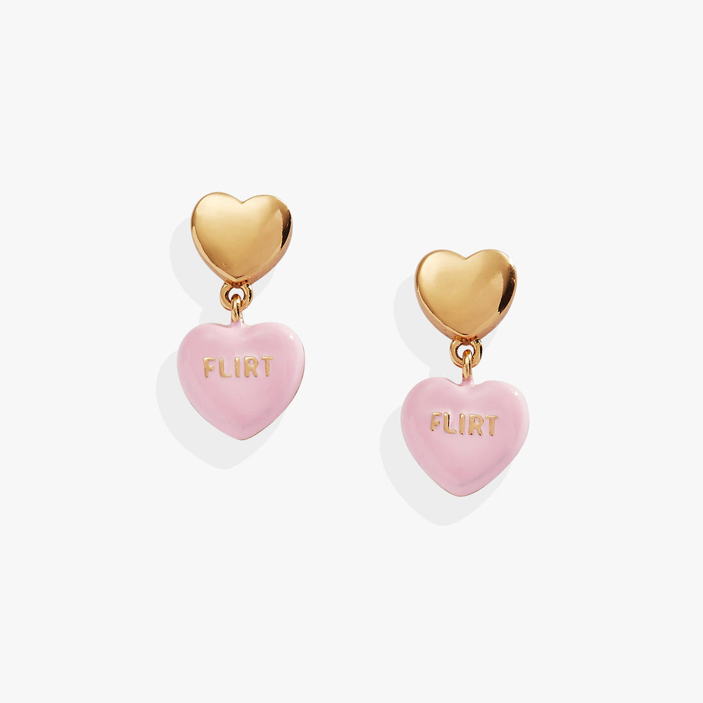 Gold stud earrings with pink heart-shaped charms featuring the word Flirt, inspired by Sweethearts candy.