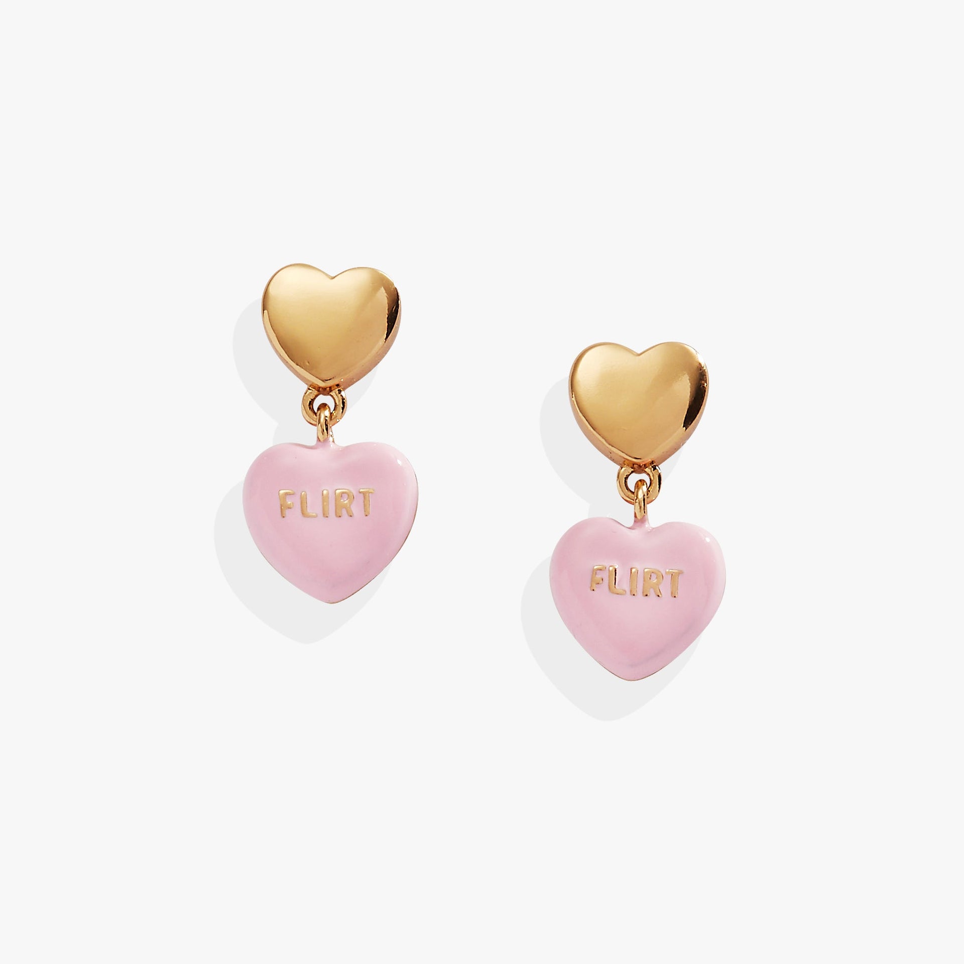 Gold stud earrings with pink heart-shaped charms featuring the word Flirt, inspired by Sweethearts candy.