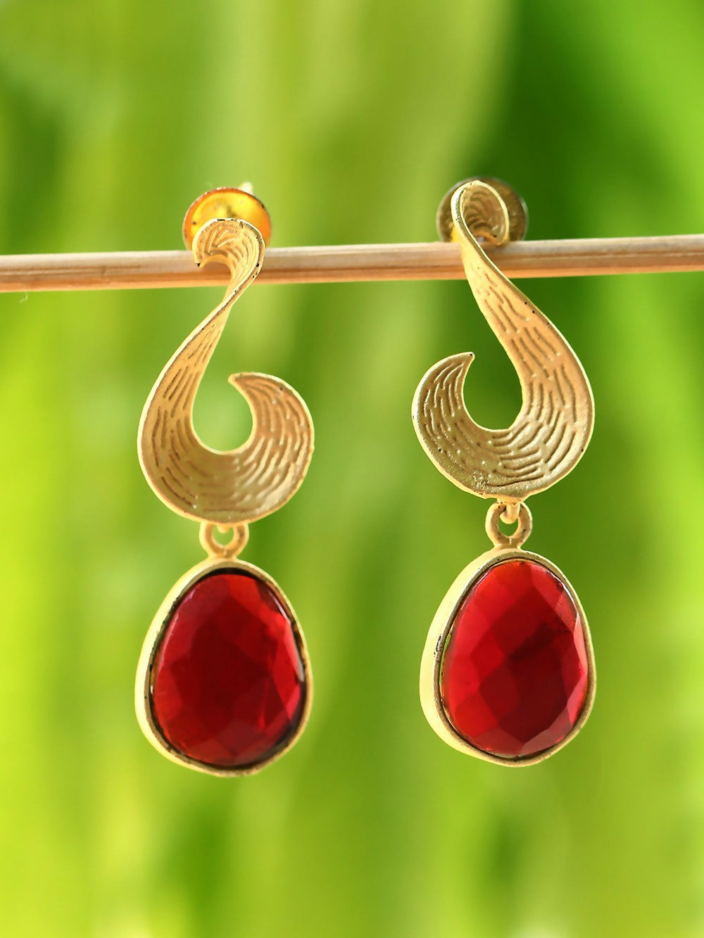 Matte gold drop earrings with a vibrant red stone detail