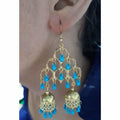 Long gold-polished double jhumka earrings with blue pearl embellishments