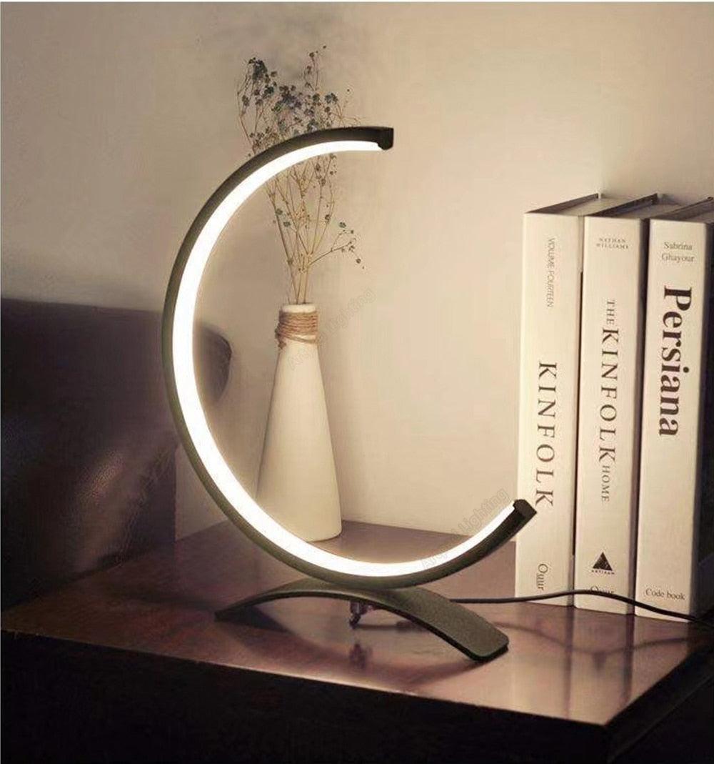 Contemporary black C-shaped LED table lamp on a modern side table.