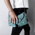 Bohemian style teal and blue sari silk tasseled clutch on a neutral background