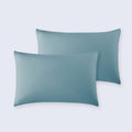 A set of two soft, blue cooling pillowcases on a white bed sheet.