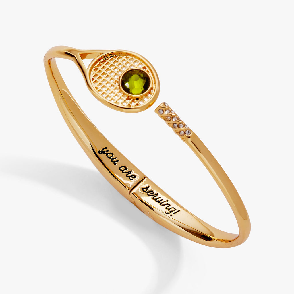 Shiny gold-tone hinge cuff bracelet featuring a tennis racket motif with peridot and crystal pavé details.