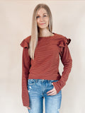 Brick red long sleeve top with ruffle shoulder detail and striped pattern