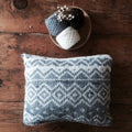 Geometric knit throw pillow in neutral white and grey colors, styled on a modern sofa