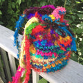 A vibrant, multicolored crochet bucket bag made from recycled sari silk yarn.