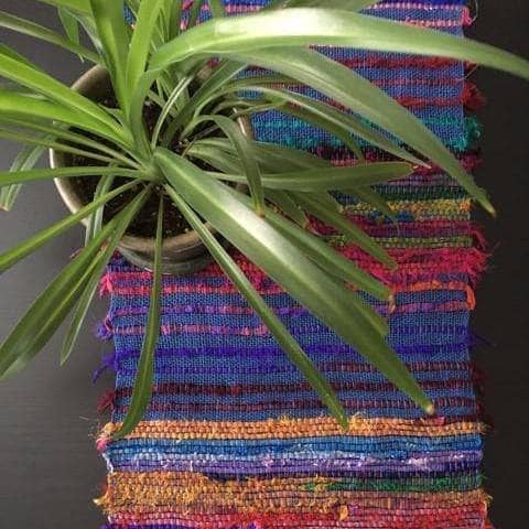 Close up of Tibet Jewels woven table runner featuring vibrant sari silk ribbons and blue linen yarn.
