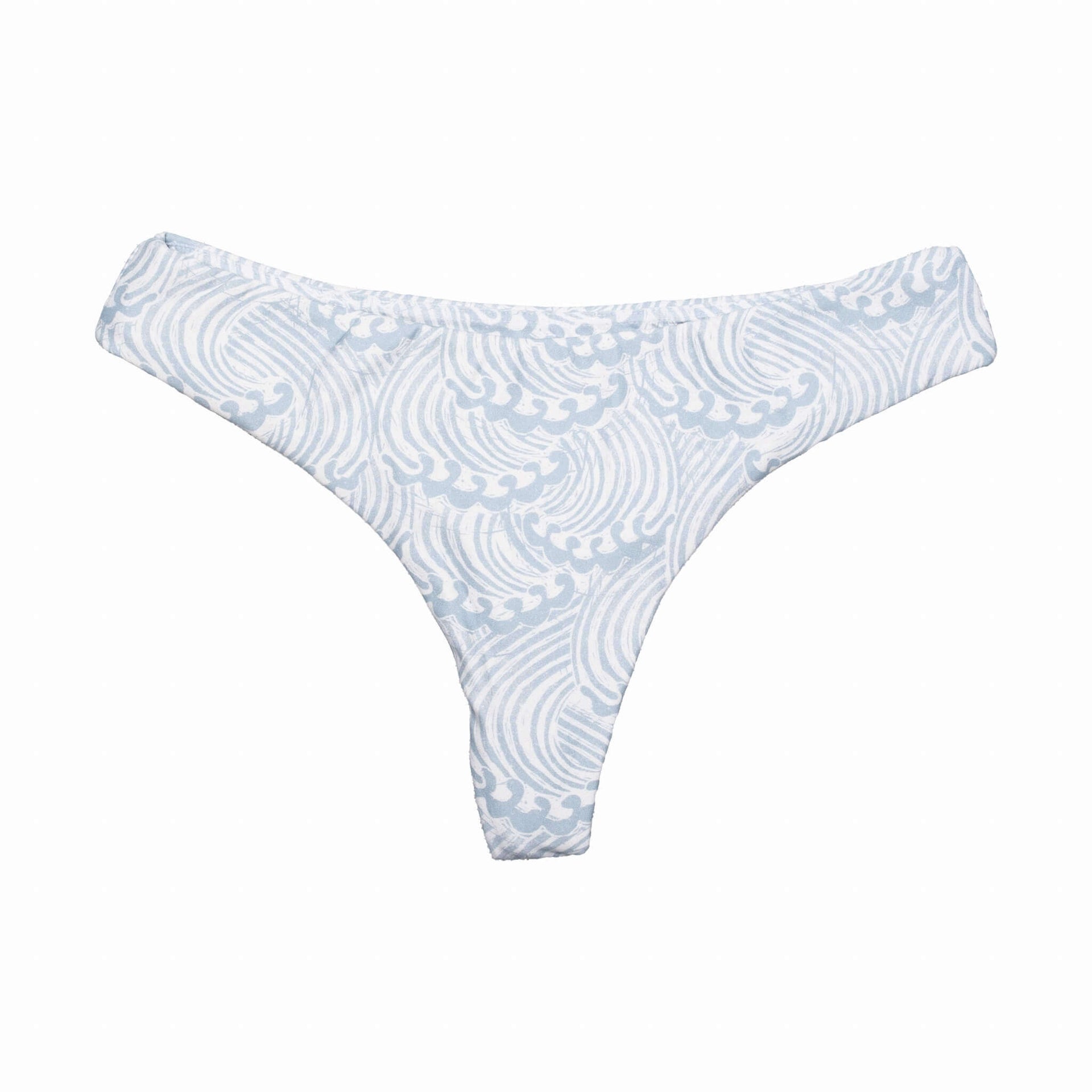 Model wearing a white cheeky Whale Tale bikini bottom in a minimalist coastal setting.