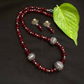 Close up of a red Radha Krishna Tanjore painting pendant on a beaded necklace chain