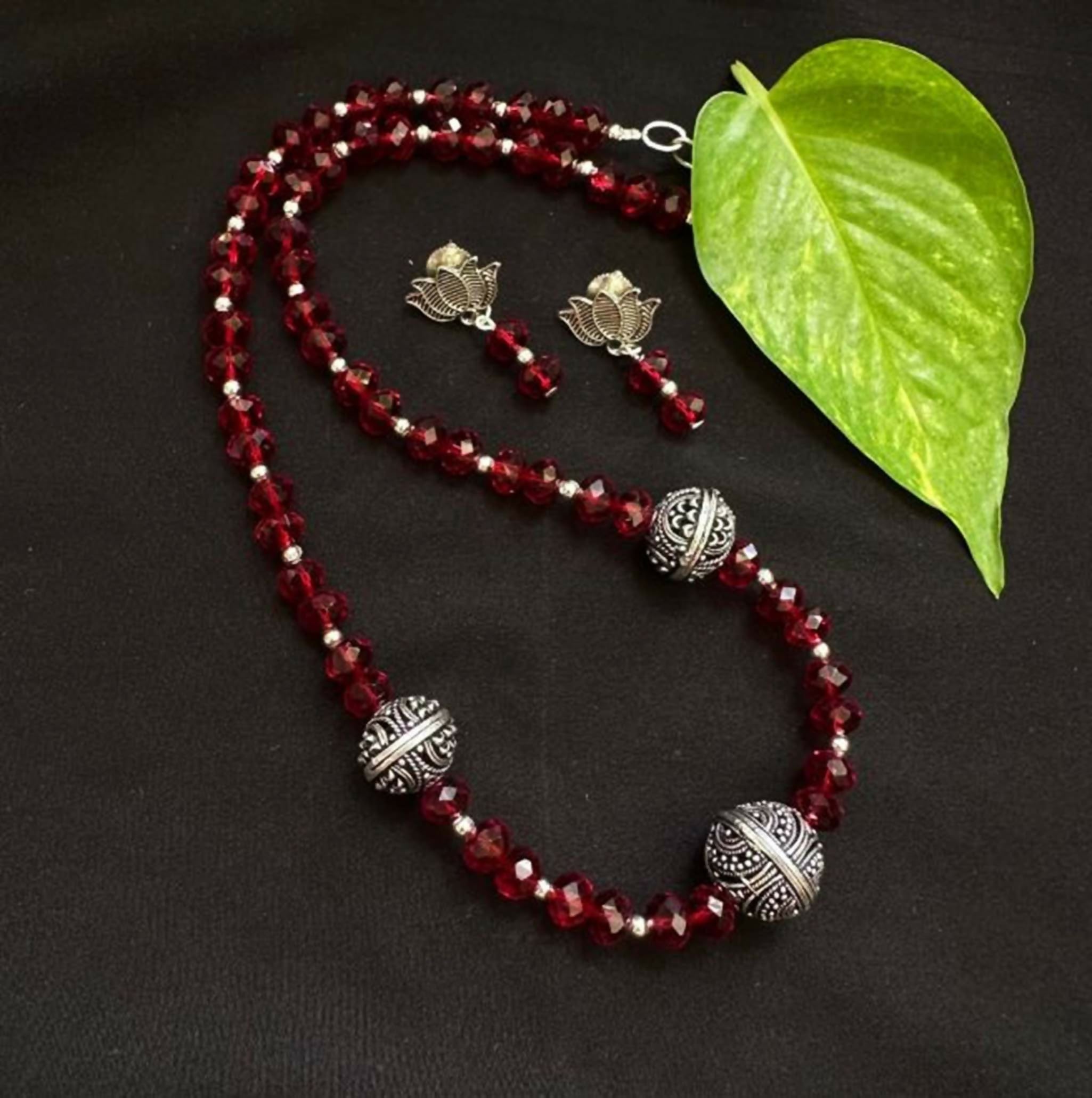 Close up of a red Radha Krishna Tanjore painting pendant on a beaded necklace chain