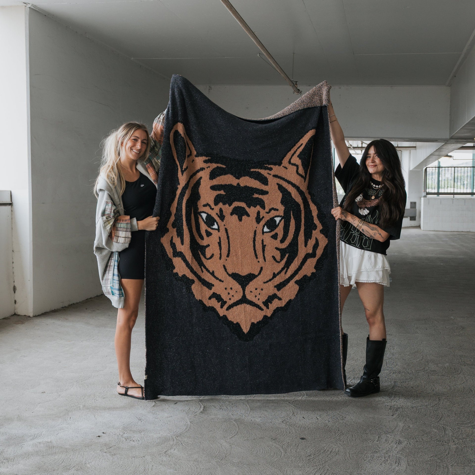 A plush black and camel tiger print knit throw blanket draped over a modern sofa in a cozy living room setting.