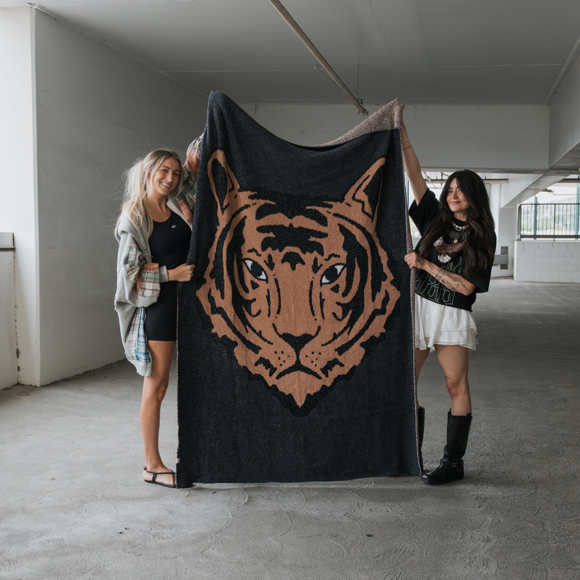 A plush black and camel tiger print knit throw blanket draped over a modern sofa in a cozy living room setting.
