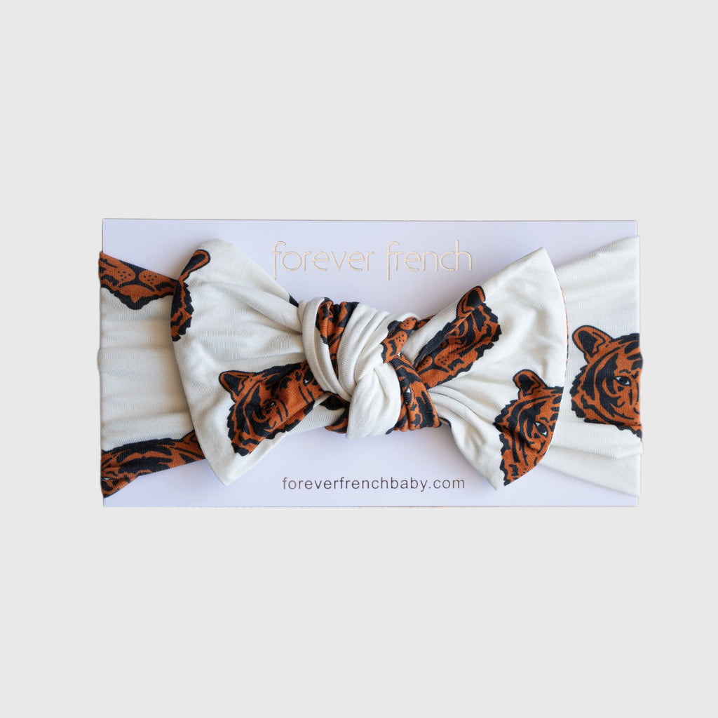 Baby wearing a silky-soft white and orange tiger print bamboo bow head wrap