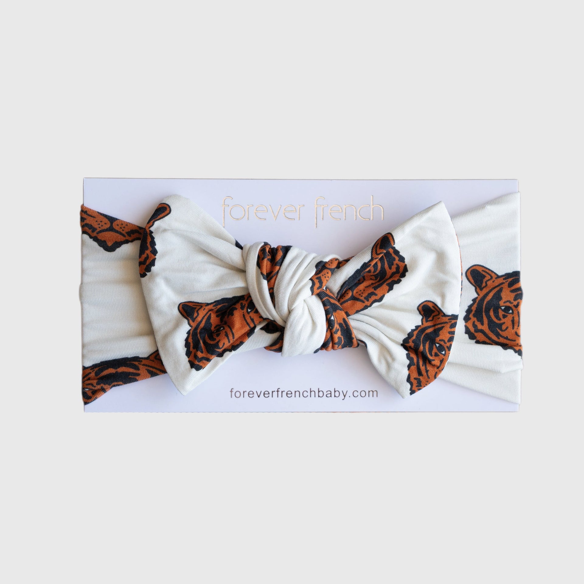 Baby wearing a silky-soft white and orange tiger print bamboo bow head wrap