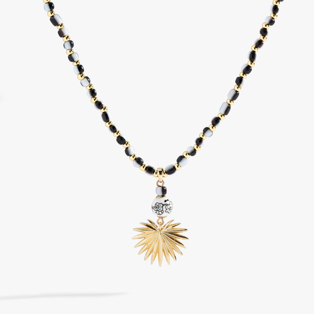 Toile Beaded Palm Pendant Necklace featuring black and white glass beads and a satin gold palm frond pendant