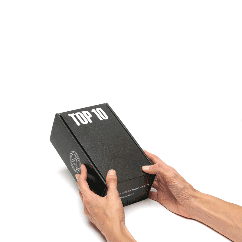 A pair of hands holding a black Top 10 herbal tea sampler box.