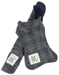 A small dog sitting on a matching reversible windowpane plaid dog mat, wearing a matching plaid dog jacket.