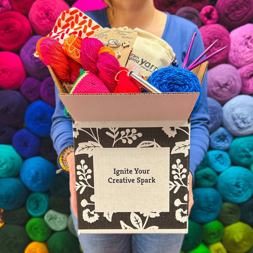 A curated collection of colorful, premium yarns inside a Darn Good Yarn Editor's Box craft supply kit.