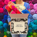 A curated collection of colorful, premium yarns inside a Darn Good Yarn Editor's Box craft supply kit.